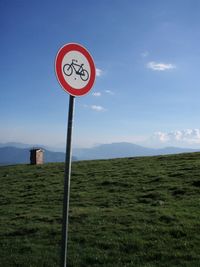 Road sign on field against sky