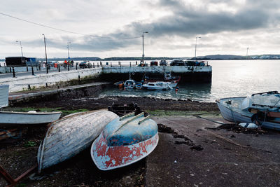 Boats moored at harbor against sky