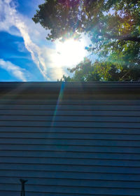 Low angle view of sunlight streaming through tree against sky