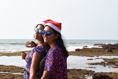 Woman with sunglasses on beach against clear sky