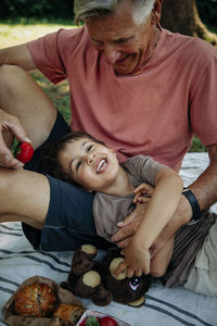 Grandfather tickling grandson during picnic at park