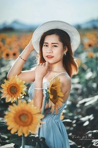 Portrait of beautiful young woman standing by flowering plants