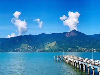 Scenic view of sea and mountains against blue sky