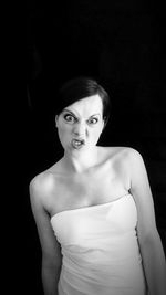 Portrait of angry woman standing against black background