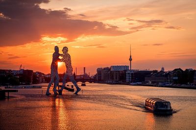 View of sculpture on bridge over river during sunset