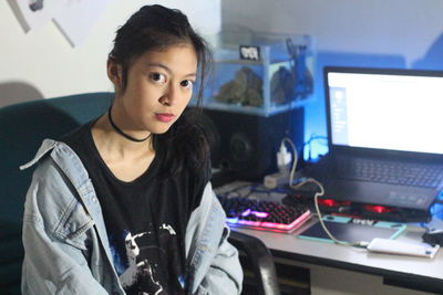 Portrait of teenage girl sitting against computer