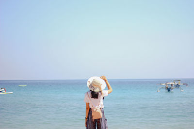 People standing on beach against clear sky