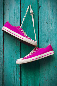 Pink shoes hanging on wooden wall