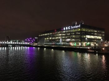 Illuminated bridge over river at night