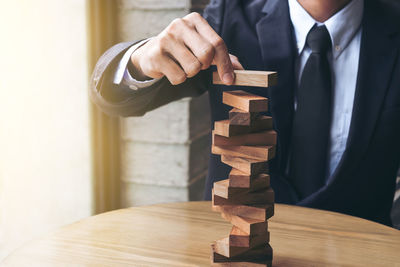 Midsection of businessman stacking wooden blocks on table
