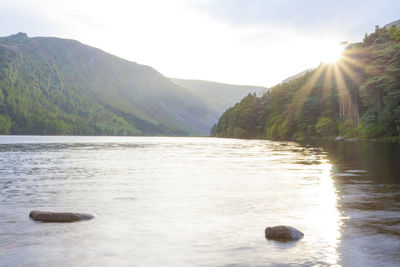 Scenic view of lake by mountains against sky