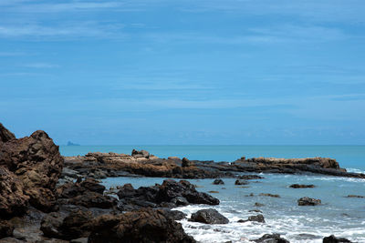 Rocks on beach against blue sky