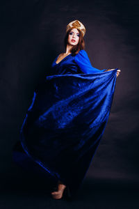 Portrait of beautiful woman in traditional clothing standing against black background