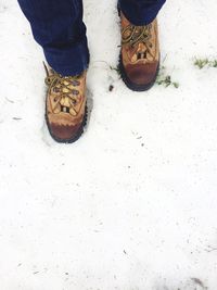 Low section of man standing on snow covered field