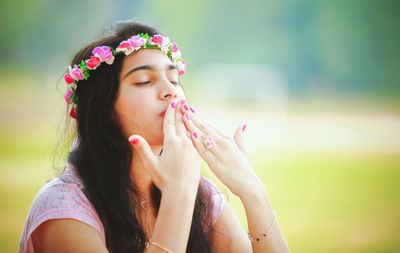 Young woman with eyes closed blowing kiss in park