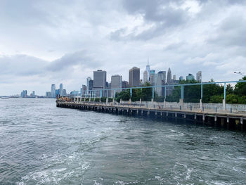 Sea by buildings against sky in city