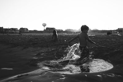 Man playing in water against clear sky