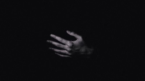 Close-up of human hand against black background