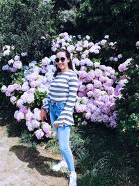 Portrait of woman standing by pink flowering plants