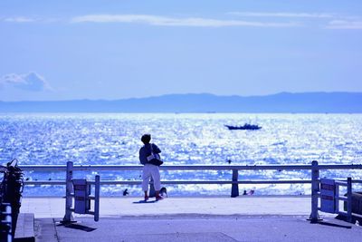 Rear view of man looking at sea against sky