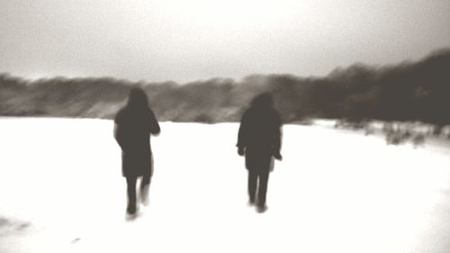 Rear view of silhouette people walking on snow covered landscape
