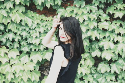 Portrait of woman standing against ivy leaves