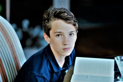 Portrait of boy reading book while sitting at home