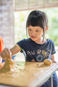 Close-up of girl making craft with mud on table