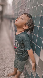 Boy looking away while standing on tiled floor