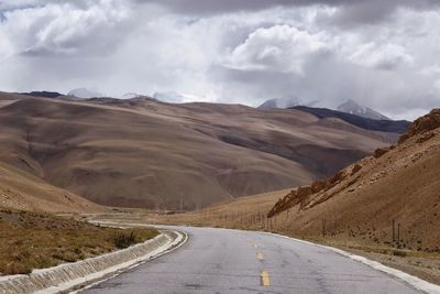 Empty road by mountains against sky