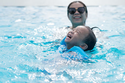 High angle view of mother and cute son enjoying in swimming pool