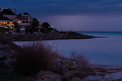 Scenic view of sea and houses against sky at sunset