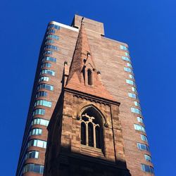 Low angle view of church tower against modern skyscraper