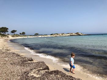 Boy on beach against clear sky