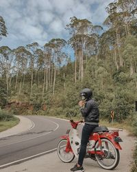 Man riding bicycle on road against trees