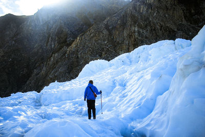 Rear view of man on snowcapped mountains during winter