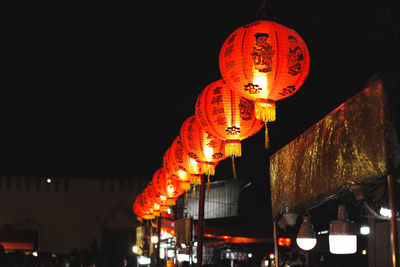 Low angle view of illuminated lanterns hanging at night