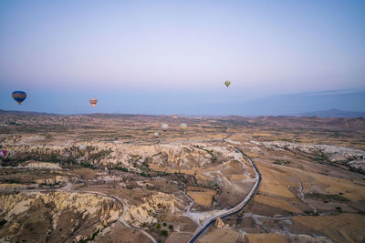 Hot air balloons flying over landscape against sky