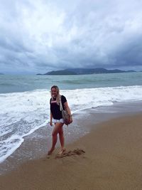 Full length portrait of young woman standing on beach