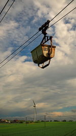 Low angle view of overhead cable cars on field against sky