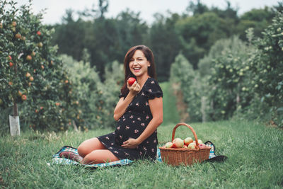 Young woman smiling while sitting on grass in field