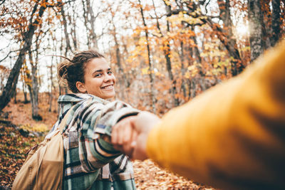 Smiling woman holding hand in autumn forest