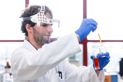 Side view of scientist examining chemical in laboratory