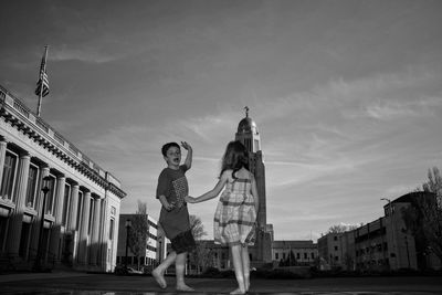 Girl and boy standing against nebraska state capitol building 