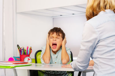 Boy screaming while sitting at classroom