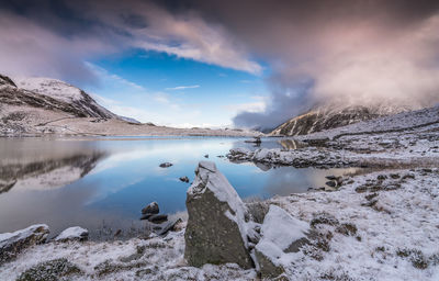 Scenic view of lake by snowcapped mountains against sky