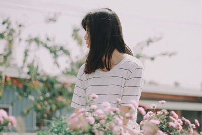 Woman looking away while standing by plants