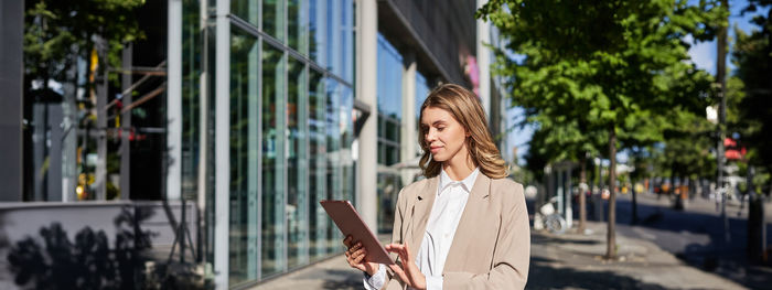 Portrait of young woman standing against buildings