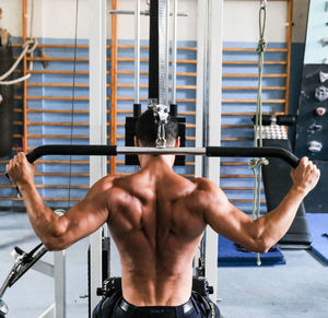 Rear view of shirtless man looking at camera