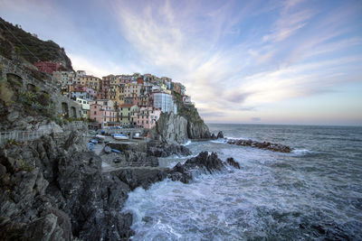 Buildings by sea against sky